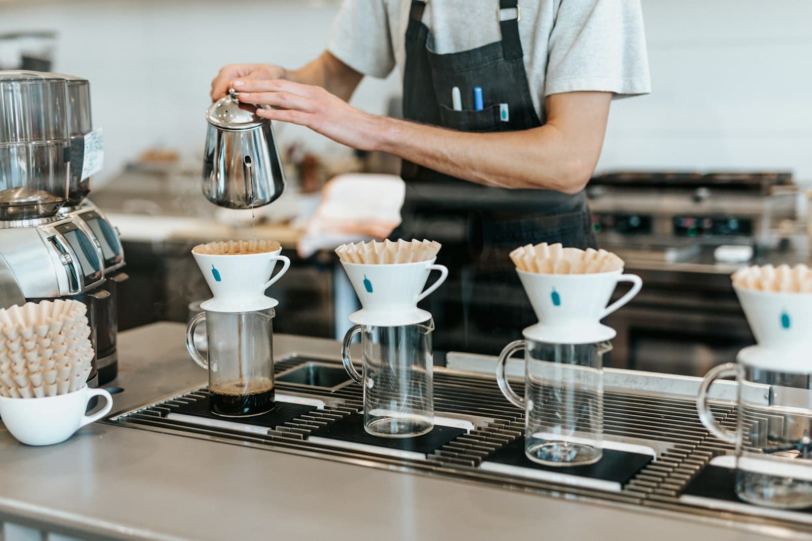 A barista brewing a row of pour-over coffees at Cafe Baguio